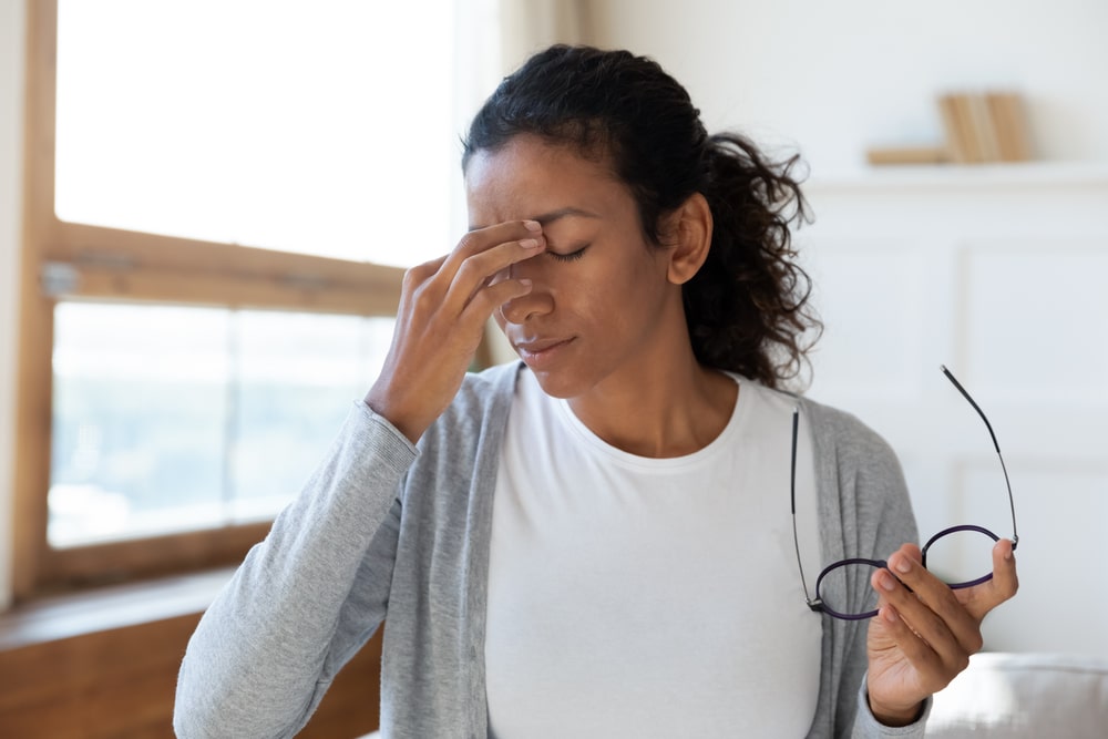 Tired woman take off glasses suffer from migraine